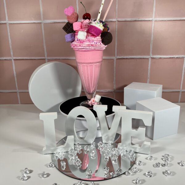 Faux Strawberry Milkshake Display Topped with Mini Donut, Cupcake, Marshmallows, Chocolate, and Cherry Delight for Decor Enthusiasts.